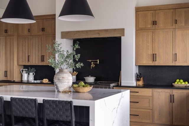 modern kitchen design with white oak cabinets and bold black backsplash and a marble kitchen island